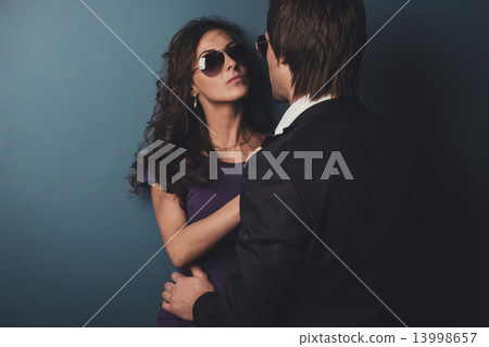 Stunning girl in glasses next to wall and her man front of her. Stunning girl in glasses next to wall and her man front of her. 13998657
