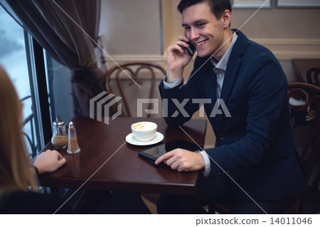 Handsome entrepreneur enjoying his launch in a cafe talking with someone by the phone. Handsome entrepreneur enjoying his launch in a cafe talking with someone by the phone. 14011046