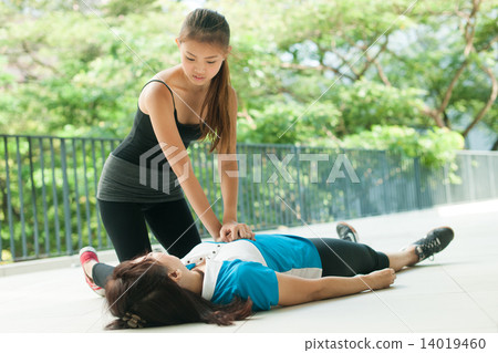 asian teenage girl doing cpr on middle aged woman 14019460