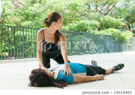 asian teenage girl doing cpr on middle aged woman and calling for help 14019465