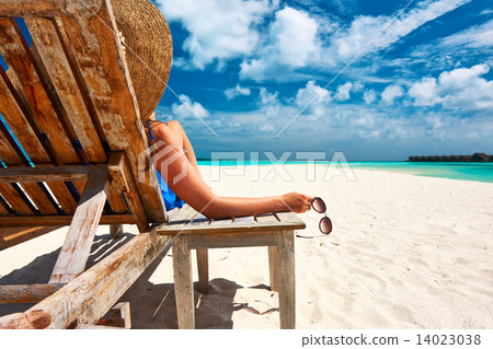 Woman at beach holding sunglasses 14023038