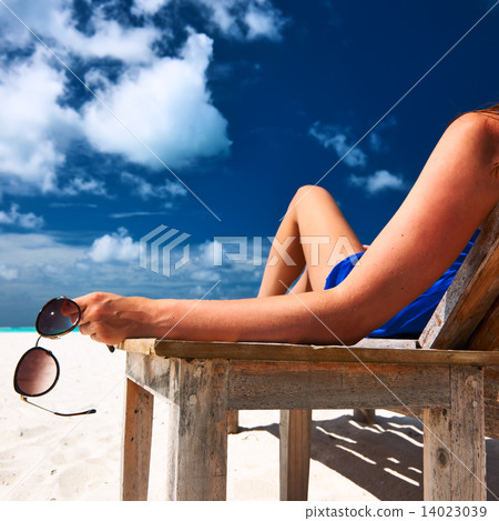 Woman at beach holding sunglasses 14023039