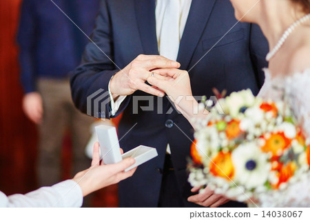 Bride putting the ring on groom's finger Bride putting the ring on groom's finger 14038067