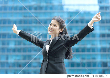 Successful chinese businesswoman celebrating arms in front of blue glass office building 14040603