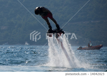 Flyboarder diving headfirst with inflatable in background Flyboarder diving headfirst with inflatable in background 14042823