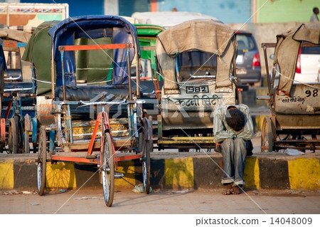 Man sitting next to rickshaws Man sitting next to rickshaws 14048009
