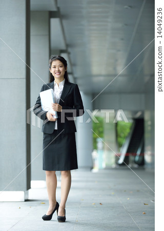 Successful chinese businesswoman holding document along office building walkway 14049236
