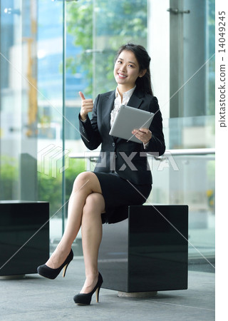 Successful chinese businesswoman giving thumb up gesture using tablet iPad sitting along promenade 14049245