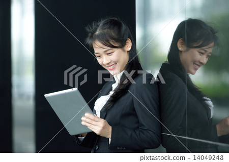 Successful chinese businesswoman using tablet iPad along office promenade Successful chinese businesswoman using tablet iPad along office promenade 14049248