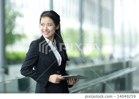 Successful chinese businesswoman using tablet iPad along office promenade Successful chinese businesswoman using tablet iPad along office promenade 14049259