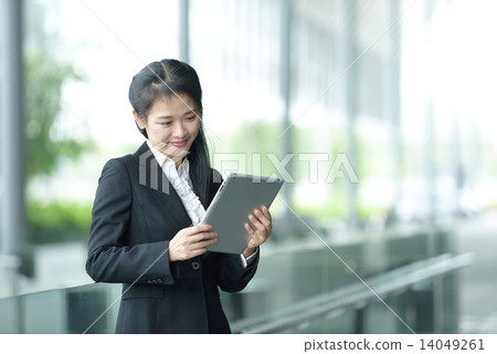 Successful chinese businesswoman using tablet iPad along office promenade Successful chinese businesswoman using tablet iPad along office promenade 14049261