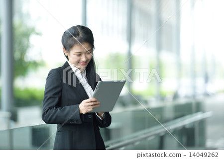 Successful chinese businesswoman using tablet iPad along office promenade Successful chinese businesswoman using tablet iPad along office promenade 14049262