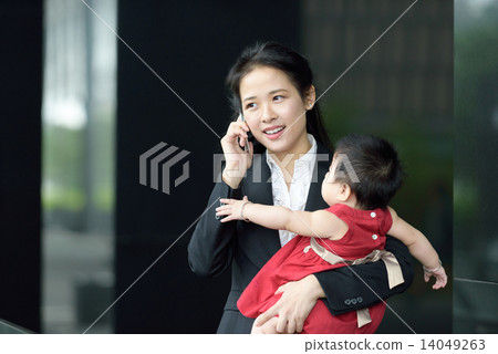 Chinese working mother carrying baby making mobile call Chinese working mother carrying baby making mobile call 14049263