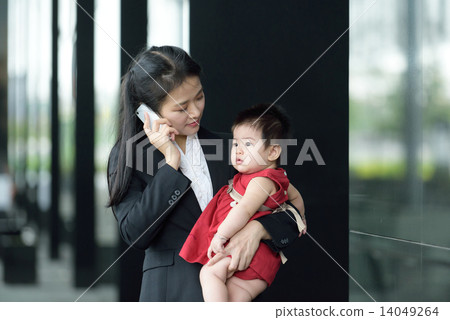 Chinese working mother carrying baby making mobile call Chinese working mother carrying baby making mobile call 14049264