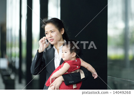 Chinese working mother carrying baby making mobile call Chinese working mother carrying baby making mobile call 14049268