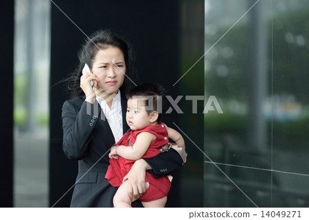 Chinese working mother carrying baby making mobile call Chinese working mother carrying baby making mobile call 14049271