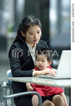 Chinese working mother taking care of daughter while using laptop Chinese working mother taking care of daughter while using laptop 14049274