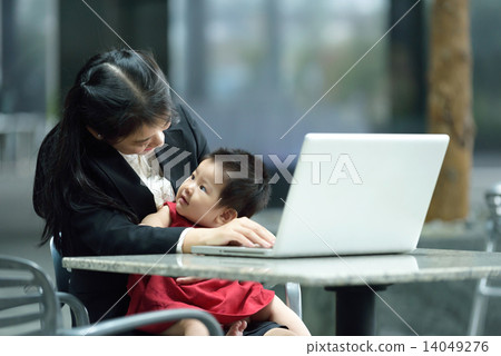 Chinese working mother taking care of daughter while using laptop 14049276