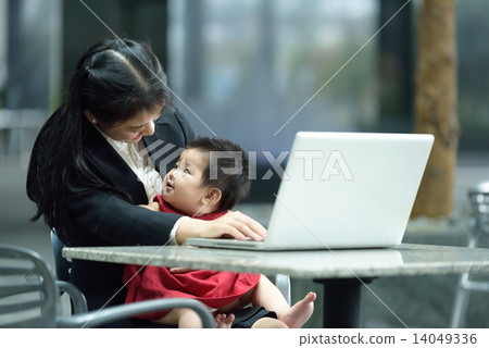 Chinese working mother taking care of daughter while using laptop Chinese working mother taking care of daughter while using laptop 14049336