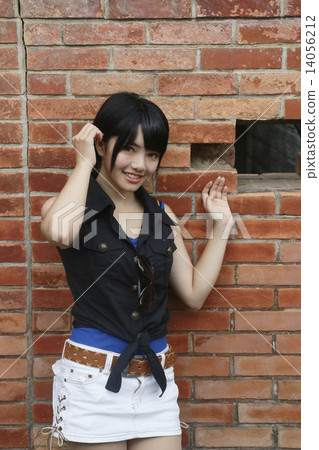 A girl posing in front of a brick wall 14056212
