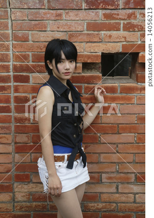A girl posing in front of a brick wall 14056213