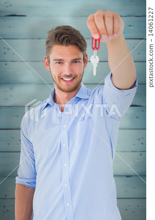 Composite image of handsome young man showing new house key Composite image of handsome young man showing new house key 14061227