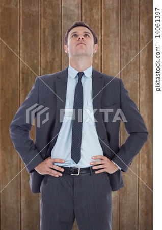 Composite image of serious businessman with hands on hips Composite image of serious businessman with hands on hips 14061397