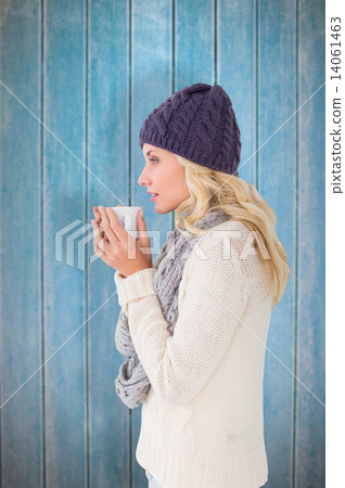 Composite image of pretty blonde in winter fashion holding mug 14061463