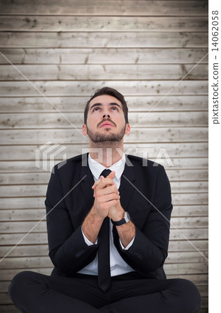 Composite image of businessman sitting praying and looking up Composite image of businessman sitting praying and looking up 14062058