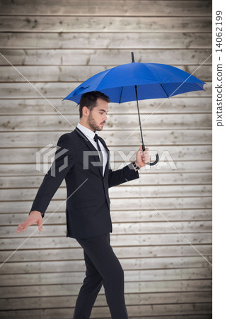 Composite image of concentrated businessman holding umbrella whi Composite image of concentrated businessman holding umbrella whi 14062199
