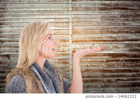 Composite image of blonde in winter clothes with hand out 14062221