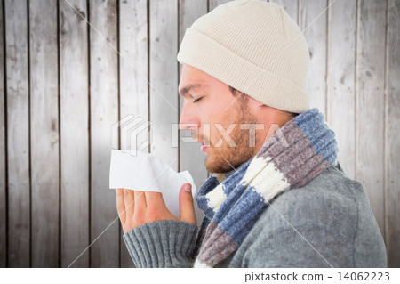Composite image of handsome man in winter fashion blowing his no 14062223
