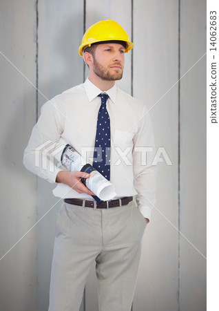 Composite image of young architect posing with hard hat and plan Composite image of young architect posing with hard hat and plan 14062683