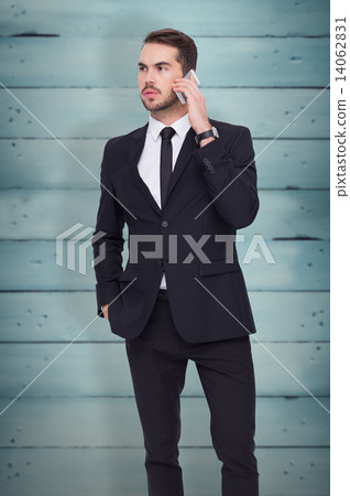 Composite image of serious businessman hand in pocket phoning Composite image of serious businessman hand in pocket phoning 14062831