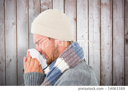 Composite image of handsome man in winter fashion blowing his no Composite image of handsome man in winter fashion blowing his no 14063389