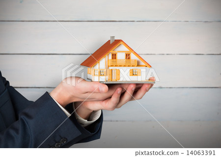 Composite image of businessman holding miniature house model Composite image of businessman holding miniature house model 14063391
