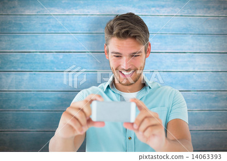 Composite image of handsome young man taking photo with smartpho Composite image of handsome young man taking photo with smartpho 14063393