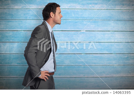 Composite image of smiling businessman with hands on hips 14063395