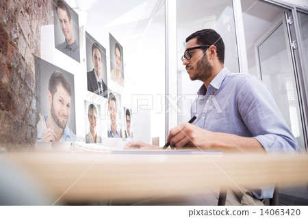 Composite image of man working at desk with computer and digitiz 14063420