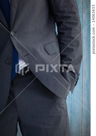 Composite image of businessman standing with hand in pocket 14063655