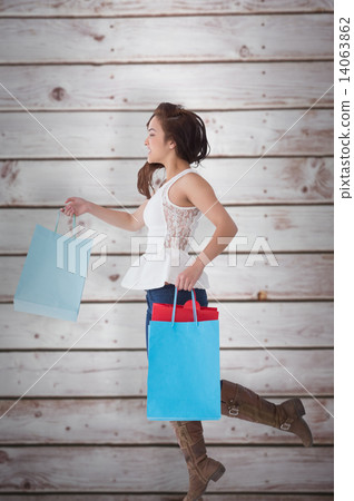 Composite image of happy brunette leaping with shopping bags 14063862