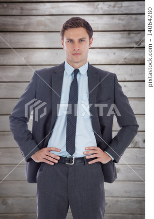 Composite image of serious businessman with hands on hips Composite image of serious businessman with hands on hips 14064280