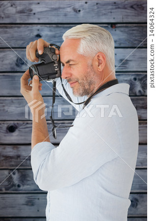 Composite image of smiling man taking a photo on digital camera Composite image of smiling man taking a photo on digital camera 14064324