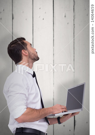 Composite image of sophisticated businessman standing using a la Composite image of sophisticated businessman standing using a la 14064659