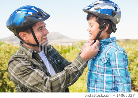 Father attaching his son cycling helmet Father attaching his son cycling helmet 14065327