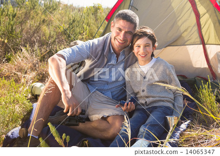 Father and son beside their tent in the countryside 14065347