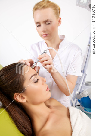 woman having a stimulating facial treatment from a therapist 14080786