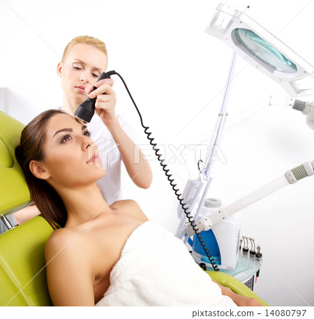 woman having a stimulating facial treatment from a therapist 14080797