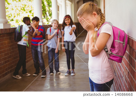 Sad schoolgirl with friends in background at school corridor 14086668