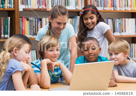Cute pupils using tablet computer in library 14086819